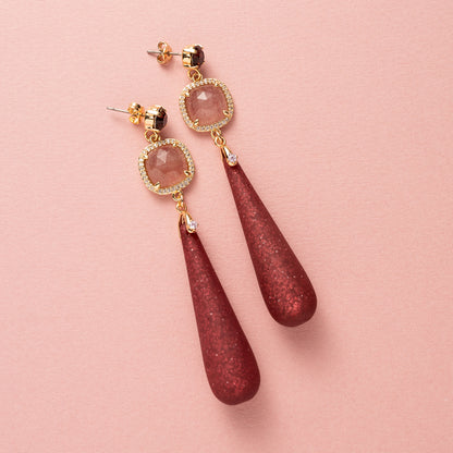 Elegante grote oorbellen, ontworpen om op te vallen. De oorstekers zijn bezet met een schitterende Swarovski puntsteen in de kleur burgundy, terwijl de donkerrode Polaris druppels een diepe, warme gloed toevoegen. De natuurlijke schoonheid van aardbeienkwarts maakt het ontwerp compleet, met een vleugje luxe en verfijning. 