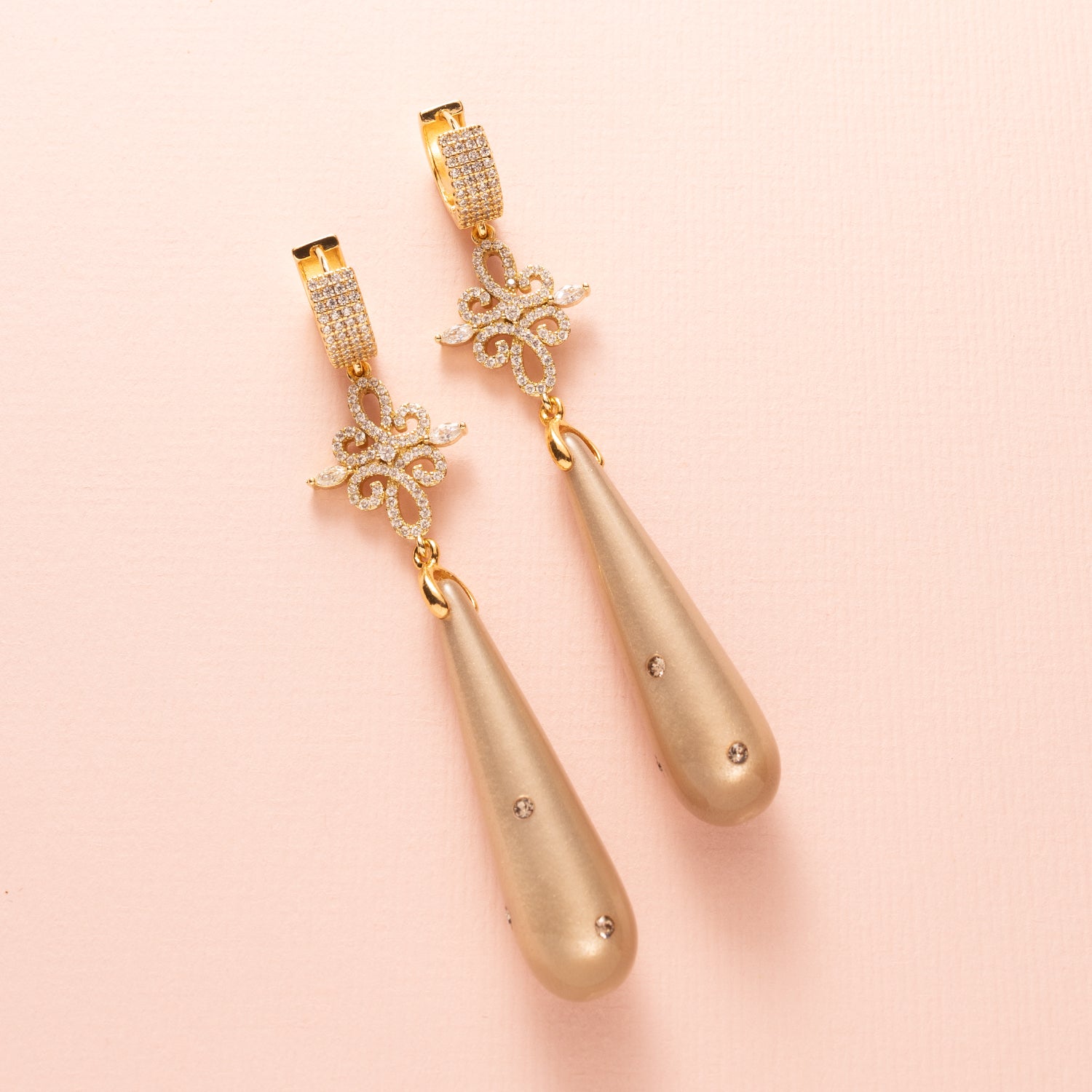 Laat je betoveren door de verfijnde elegantie van Moonlight Grace. Deze statement oorbellen combineren een zachte greige (grijs/bruine) Polaris druppel – subtiel bezet met zes fonkelende Swarovski steentjes – met een schitterend tussenstuk vol zirkonia. De oorbel sluit met elegante zirkonia oorringen die een classy sparkle toevoegen. Groot, opvallend en onweerstaanbaar stijlvol: perfect voor een avond vol allure of een chique diner.