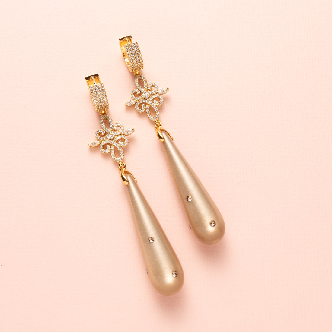 Laat je betoveren door de verfijnde elegantie van Moonlight Grace. Deze statement oorbellen combineren een zachte greige (grijs/bruine) Polaris druppel – subtiel bezet met zes fonkelende Swarovski steentjes – met een schitterend tussenstuk vol zirkonia. De oorbel sluit met elegante zirkonia oorringen die een classy sparkle toevoegen. Groot, opvallend en onweerstaanbaar stijlvol: perfect voor een avond vol allure of een chique diner.