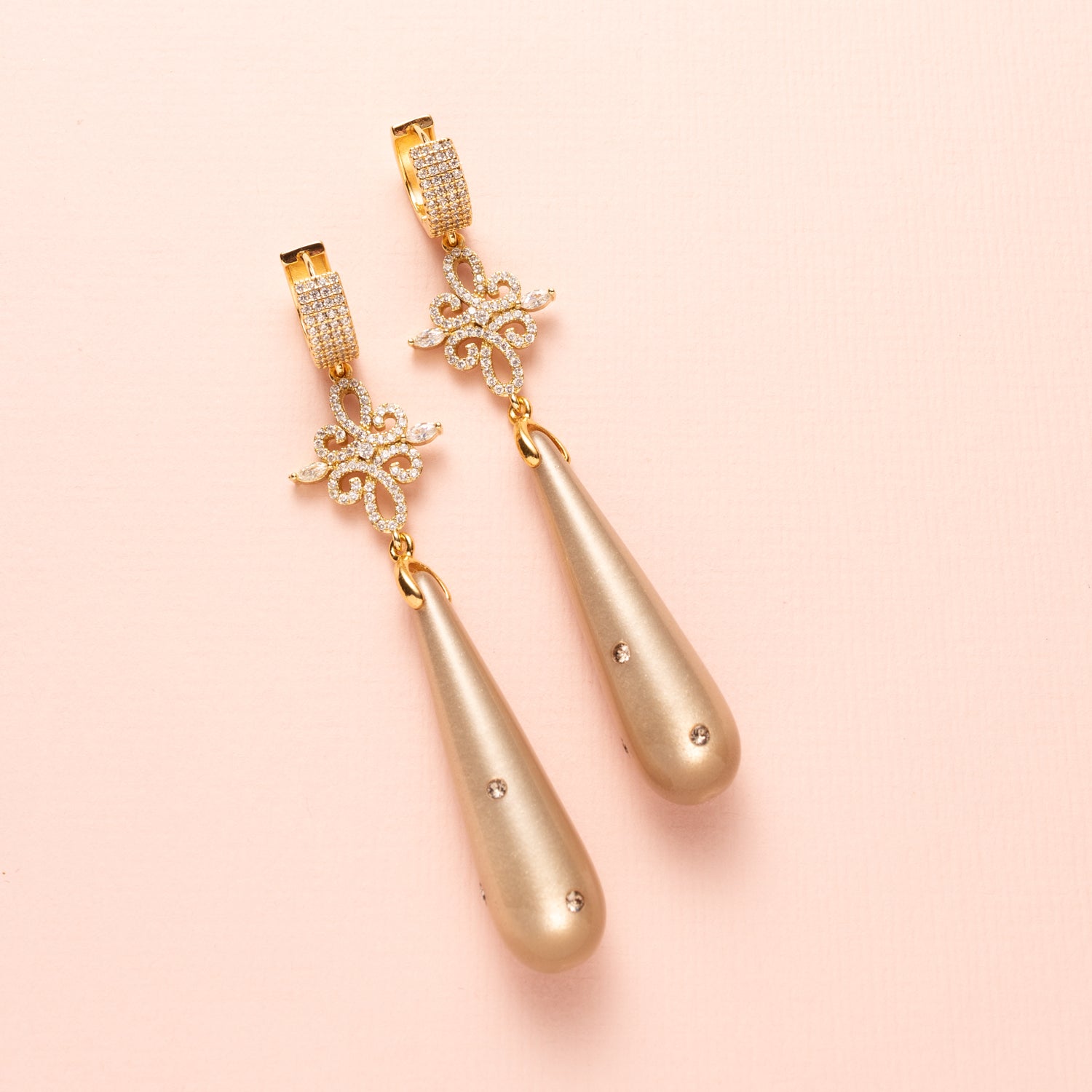 Laat je betoveren door de verfijnde elegantie van Moonlight Grace. Deze statement oorbellen combineren een zachte greige (grijs/bruine) Polaris druppel – subtiel bezet met zes fonkelende Swarovski steentjes – met een schitterend tussenstuk vol zirkonia. De oorbel sluit met elegante zirkonia oorringen die een classy sparkle toevoegen. Groot, opvallend en onweerstaanbaar stijlvol: perfect voor een avond vol allure of een chique diner.