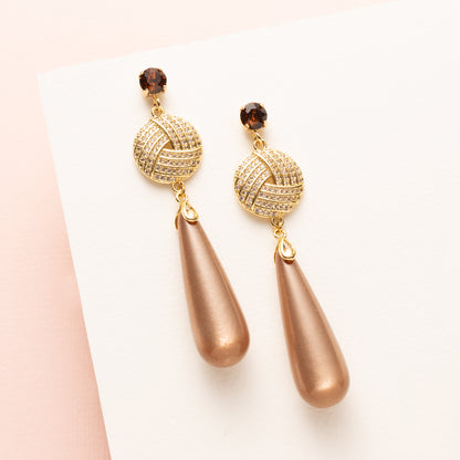 Hazel Glow combineert tijdloze elegantie met een trendkleur van dit seizoen. De oorbel heeft bruine Swarovski oorstekers, een rond zirkonia tussenstuk en glanzende Polaris druppels in warme, stijlvolle hazelnootkleur.

Een subtiele statement oorbel die moeiteloos stijl, luxe en moderne flair toevoegt aan elke look – perfect voor vrouwen die zowel klassiek als modieus willen stralen.