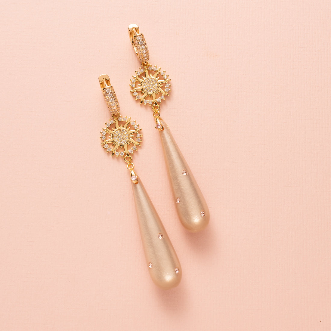 Voeg een vleugje zachte schittering toe aan je look met Rosy Luminance. Deze elegante oorbellen combineren een zacht roze polaris druppel met verfijnde roze Swarovski steentjes die een subtiel sprankelend accent geven.

Het zirkonia zon-tussenstuk brengt een stijlvolle, stralende touch die mooi contrasteert met de zachte tinten van de druppel. De zirkonia oorringen maken het geheel af met een tijdloze luxe die past van kantoor tot avond.