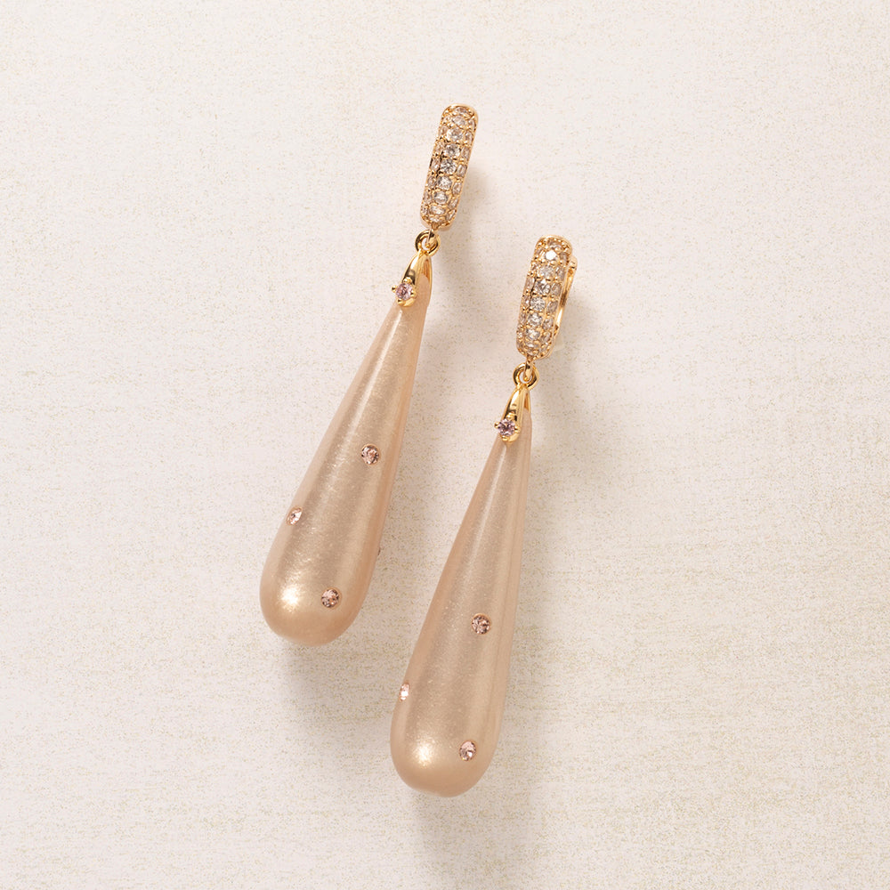 Blush Whisper is verfijning in zijn puurste vorm. Een langgerekte Polaris druppel in zacht rosé, met een parelmoerachtige glans en subtiel bezet met kleine roze Swarovski steentjes die alleen oplichten als het licht ze vindt. De druppel hangt aan een goudkleurige creool, rondom gezet met fonkelende zirkonia.

Geen tierelantijnen, juist die eenvoud maakt deze oorbel zo draagbaar. De zachte rosétint is warm en flatteus bij vrijwel elke huidtint en combineert moeiteloos bij je dagelijkse garderobe.

