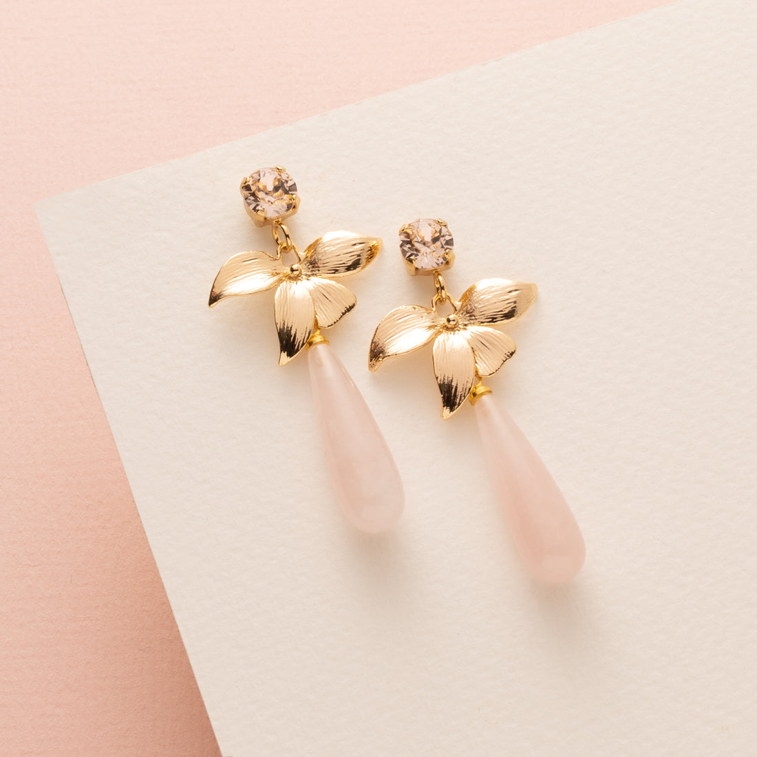 Zachtroze tinten en verfijnde details komen samen in Rose Quartz Bloom – elegante oorbellen met een vrouwelijke en tijdloze uitstraling. De Swarovski steker in de kleur Silk (lichtroze) vangt het licht op een subtiele manier, terwijl de gouden bloem zorgt voor een sierlijke overgang naar de natuurlijke rozenkwarts druppel.