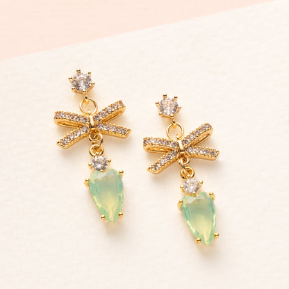 Subtiel en verfijnd: Rosebud Bow combineert kleine zirkonia oorstekers met een zeegroene druppel en een klein zirkonia strikje voor een elegante, speelse touch. Perfect voor dagelijks gebruik of een minimalistisch kleuraccent.