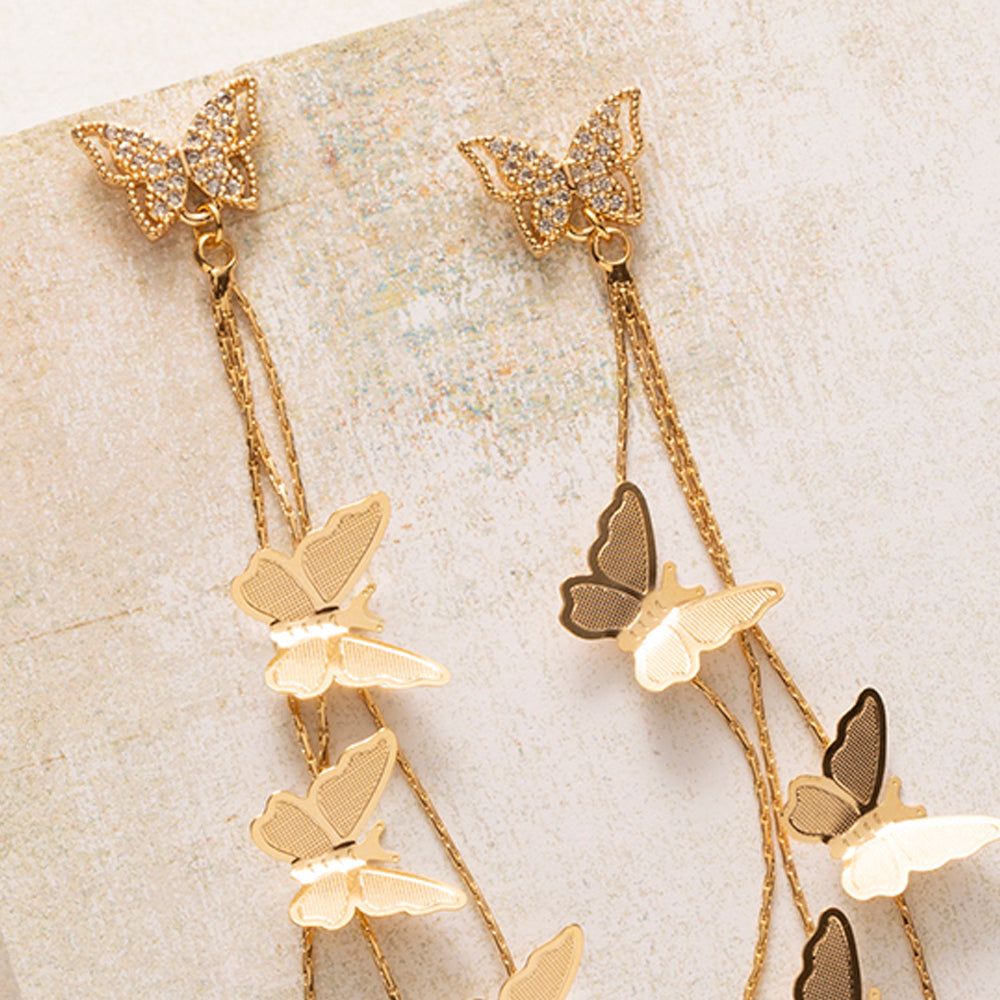 Golden Flutter is verfijnd, maar zeker niet bescheiden. Een vlinder van fonkelende zirkonia sluit mooi aan tegen het oor, en daaronder vallen fijne gouden kettinkjes met sierlijke vlinders tot 9 cm lang. Bij elke beweging vangen ze het licht.

Het ontwerp is vrouwelijk zonder zoet te worden, dankzij de strakke lijnen en het warme goud. Met je haar opgestoken komt de lengte het best tot zijn recht, of je ze nu overdag draagt of op een feestelijke avond.