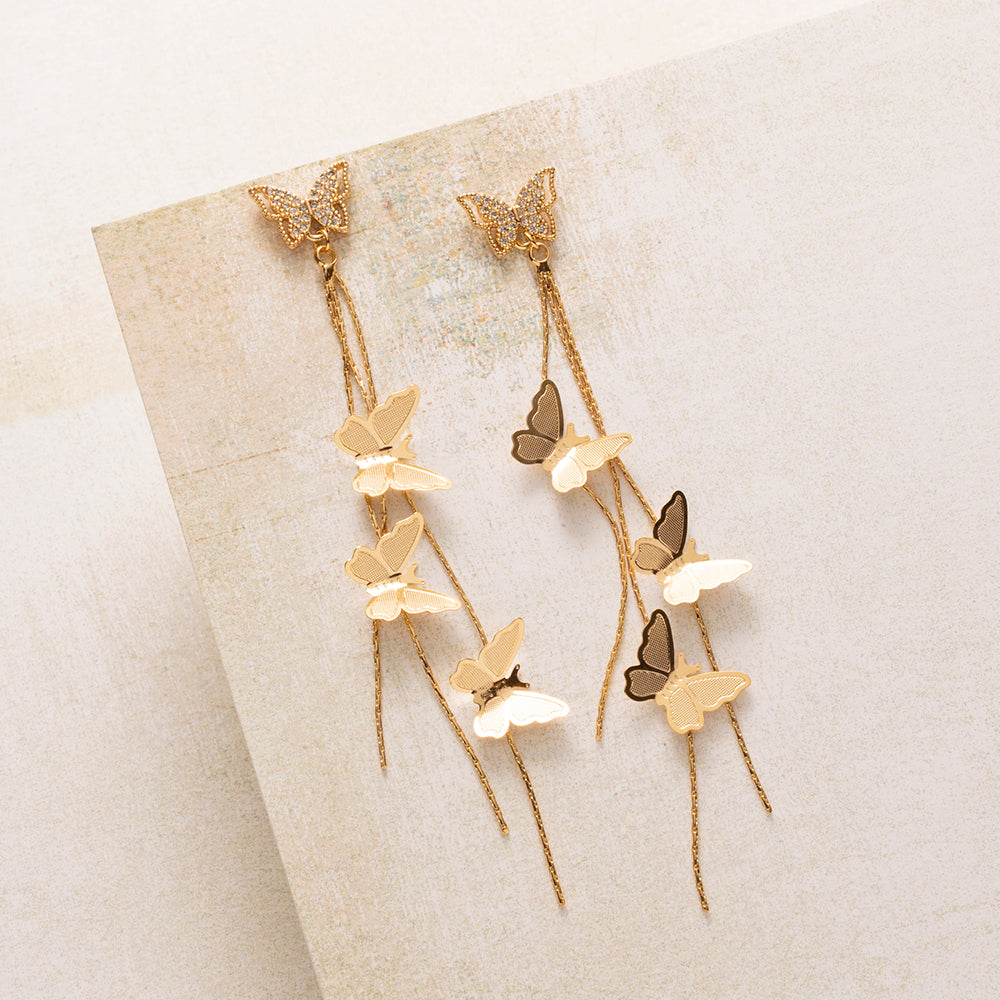 Golden Flutter is verfijnd, maar zeker niet bescheiden. Een vlinder van fonkelende zirkonia sluit mooi aan tegen het oor, en daaronder vallen fijne gouden kettinkjes met sierlijke vlinders tot 9 cm lang. Bij elke beweging vangen ze het licht.

Het ontwerp is vrouwelijk zonder zoet te worden, dankzij de strakke lijnen en het warme goud. Met je haar opgestoken komt de lengte het best tot zijn recht, of je ze nu overdag draagt of op een feestelijke avond.