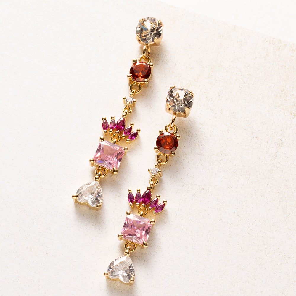 Royal Blush is een kleine verzameling juwelen in één oorbel. Onder een fonkelende Swarovski oorsteker volgen zirkonia steentjes in warm rood, fuchsia en zacht roze. Een kroontje van marquise-geslepen steentjes rust boven een vierkante roze steen, en een helder hartje vormt het slotstuk.

De kleuren lopen van diep naar licht, en de gouden zetting houdt alles verfijnd. Deze oorbellen staan mooi bij een eenvoudige outfit, maar net zo goed bij een feestelijke look.