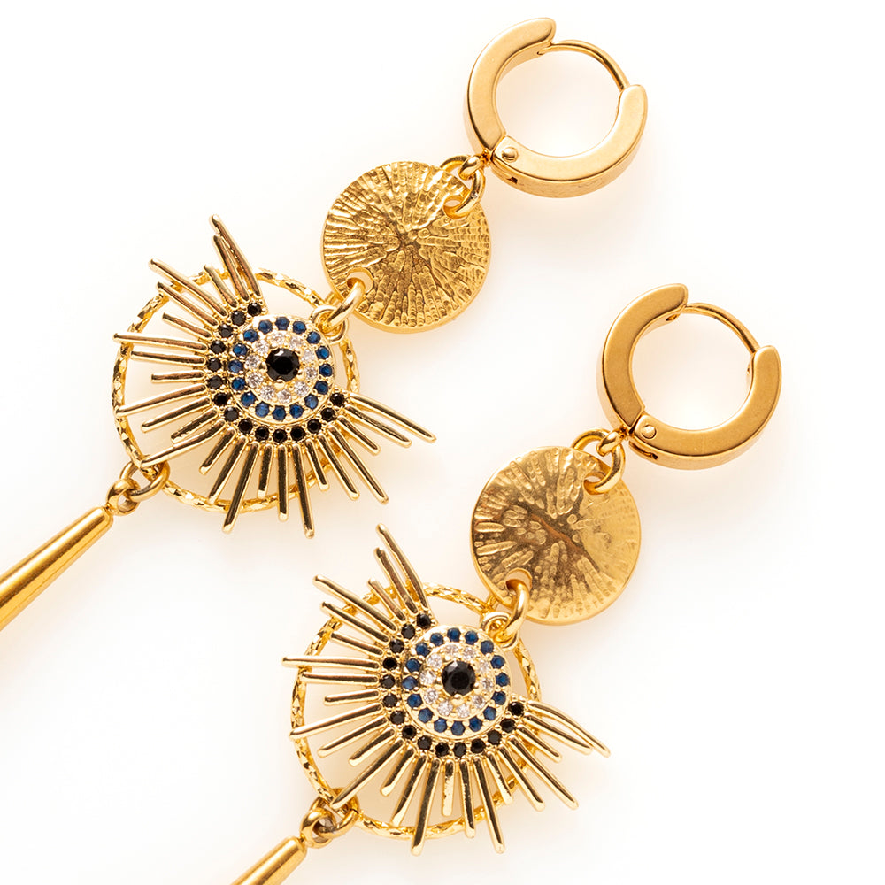 Midnight Sun combineert warm goud met zwarte zirkonia, en dat maakt deze oorbellen stoer en krachtig. De uitwaaierende stralen en de lange gouden hanger zorgen voor een groot, uitgesproken silhouet dat van een afstand al opvalt.

Bij een zwarte coltrui zijn ze stoer, bij een avondjurk dramatisch. Ze maken in beide gevallen het verschil.