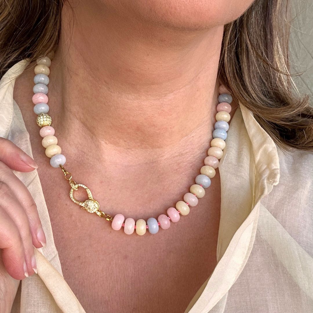Een speelse knipoog naar de nostalgische snoepjeskettingen, maar dan modern en stijlvol. Deze ketting combineert zachte pasteltinten van Jade met levendige felroze kraaltjes voor een frisse en opvallende uitstraling. Halverwege schittert een zirkonia kraal en aan de voorkant pronkt een groot zirkonia slot, wat deze ketting tot een echte eyecatcher maakt. Perfect voor wie een kleurrijk en elegant statement wil dragen.