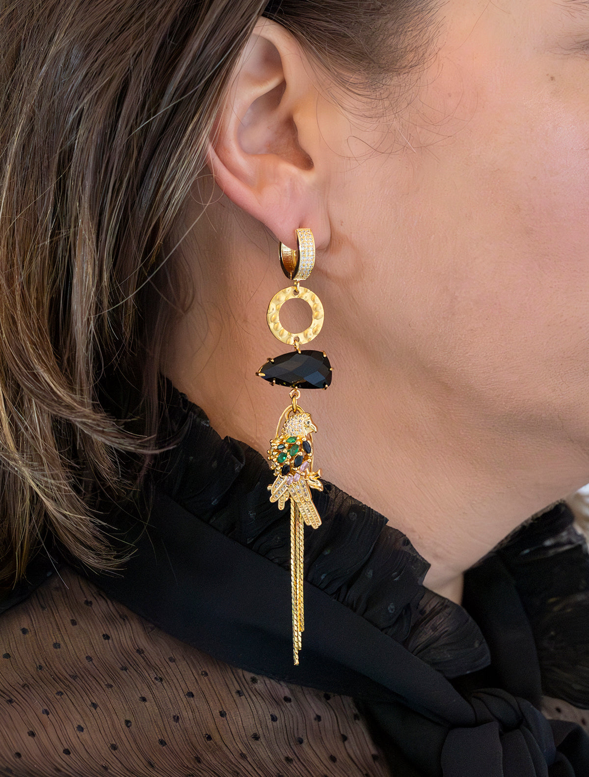 Laat je meevoeren naar de mysterieuze nachtelijke jungle met deze asymmetrische&amp;nbsp; oorbellen. Aan de ene kant schittert een elegante papegaai met diepzwarte stenen, terwijl de andere kant wordt gesierd door een stijlvol palmblad. Groot, opvallend en speels – perfect voor wie durft te stralen met een uniek design.