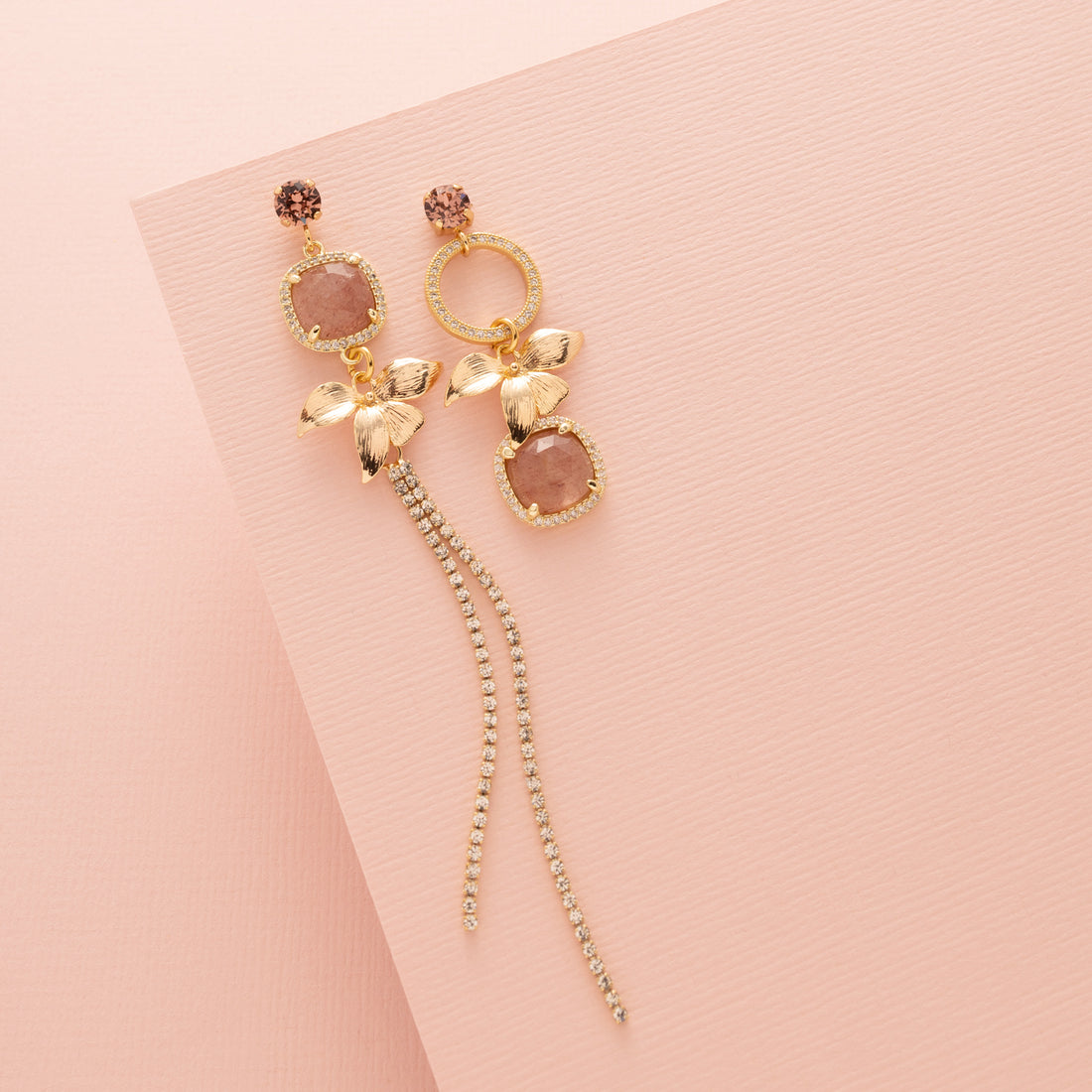 Voeg een verfijnd en vrouwelijk accent toe met de Berry Blush asymmetrische oorbellen. Deze elegante oorbellen combineren een fonkelende Swarovski oorsteker met een gouden bloem, sprankelende zirkonia cirkels en een unieke aardbeienkwarts edelsteen. De steen heeft een warme roze/rode tint die subtiel schittert bij elke beweging. Het asymmetrische ontwerp geeft een speelse twist aan deze chique oorbellen – perfect voor een diner, een bijzondere gelegenheid of als stijlvolle finishing touch voor je dagelijkse