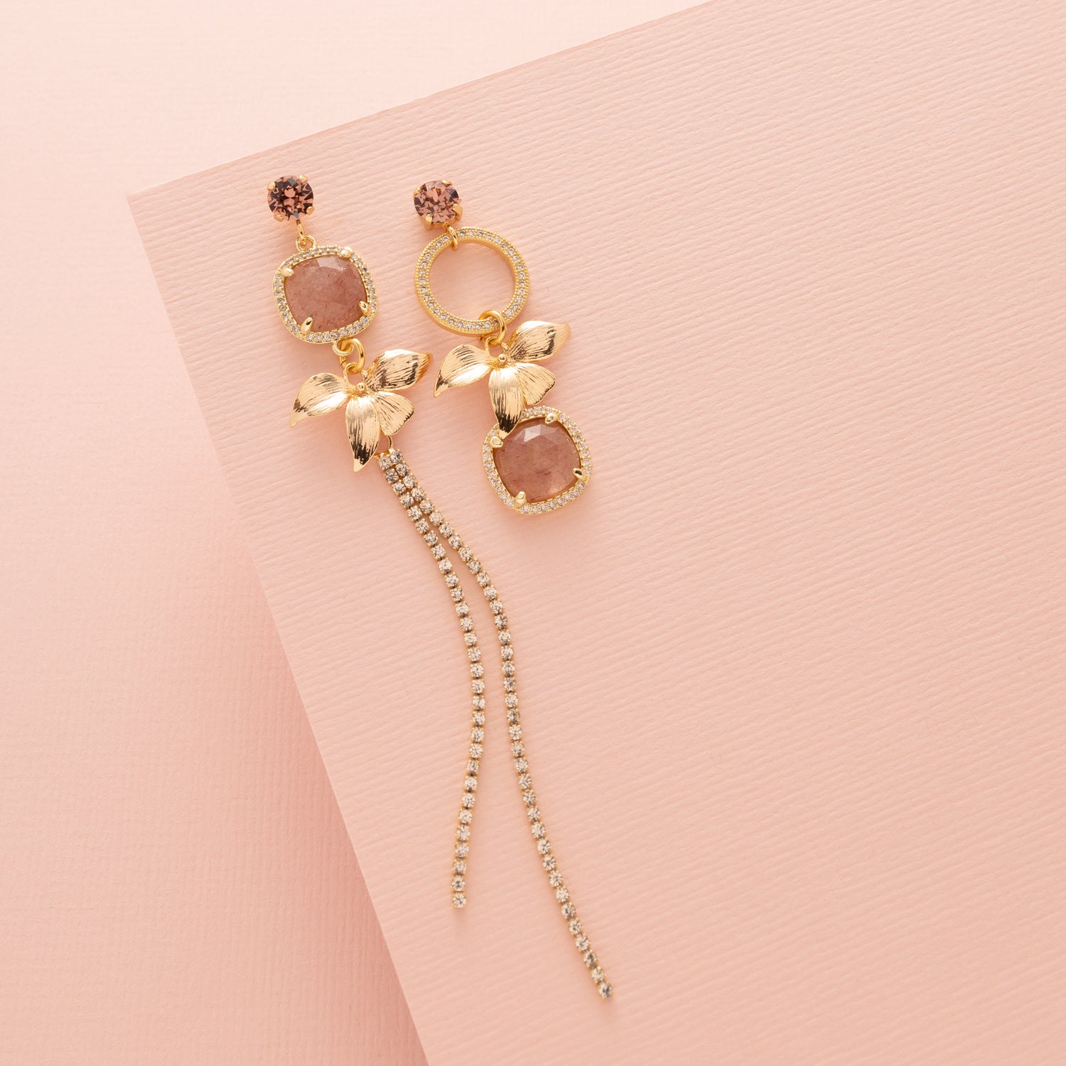 Voeg een verfijnd en vrouwelijk accent toe met de Berry Blush asymmetrische oorbellen. Deze elegante oorbellen combineren een fonkelende Swarovski oorsteker met een gouden bloem, sprankelende zirkonia cirkels en een unieke aardbeienkwarts edelsteen. De steen heeft een warme roze/rode tint die subtiel schittert bij elke beweging. Het asymmetrische ontwerp geeft een speelse twist aan deze chique oorbellen – perfect voor een diner, een bijzondere gelegenheid of als stijlvolle finishing touch voor je dagelijkse