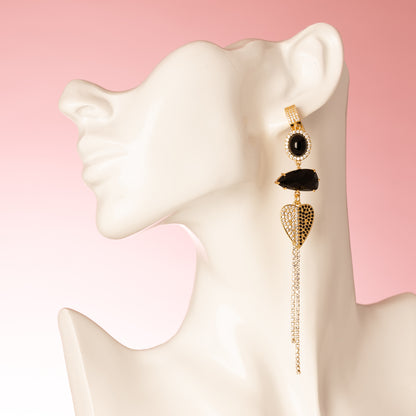 Deze handgemaakte asymmetrische statement oorbellen combineren diepe zwarte zirkonia, fonkelend kristalglas en twee verfijnde accenten: een zirkonia hart en een sierlijke vogel. Het spel tussen licht en donker, lengte en asymmetrie, maakt dit ontwerp heerlijk opvallend zonder zijn elegantie te verliezen.

Voor de vrouw die haar eigen pad volgt, die graag gezien mag worden en zich met trots onderscheidt — met een vleugje fluweelzachte luxe in elke beweging.