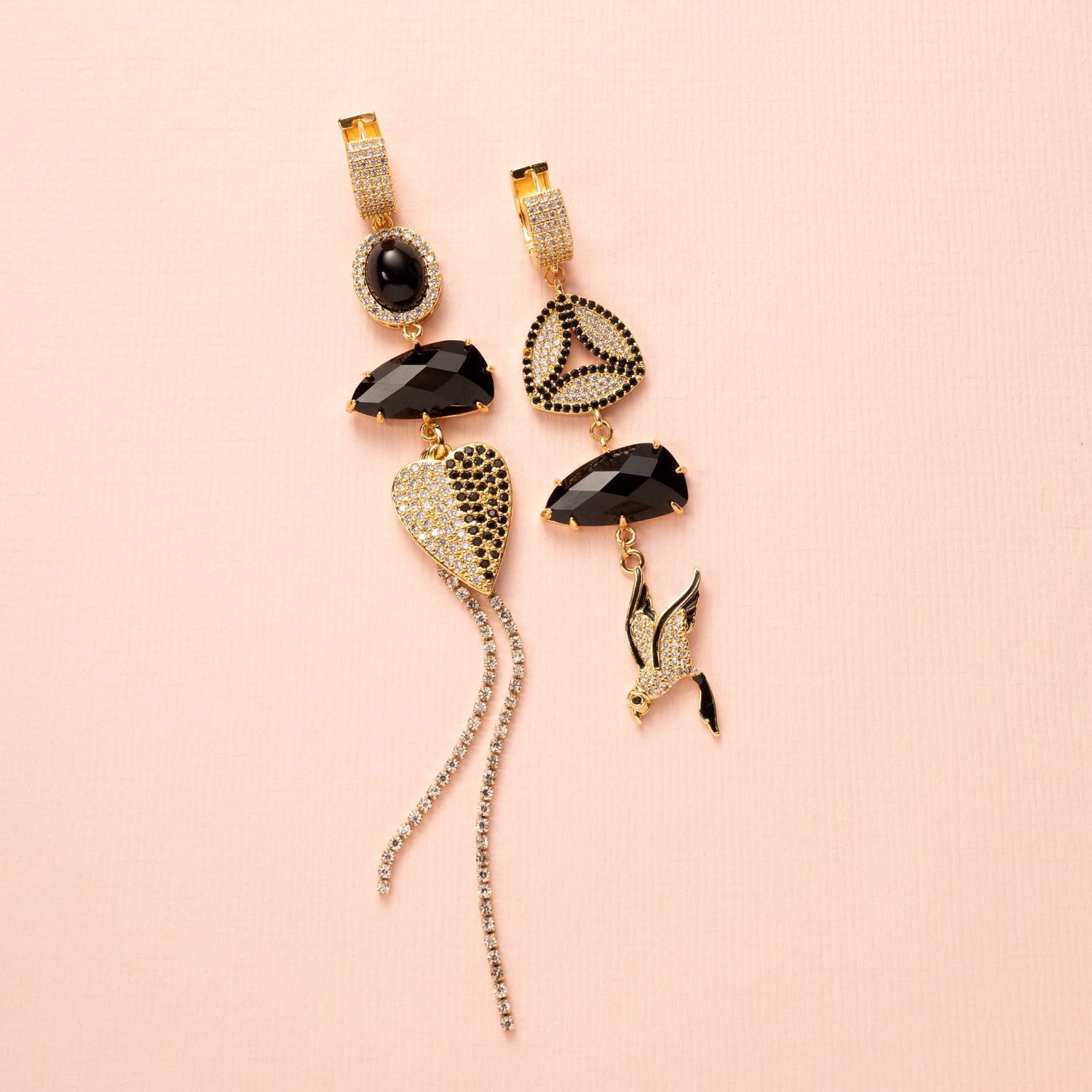Deze handgemaakte asymmetrische statement oorbellen combineren diepe zwarte zirkonia, fonkelend kristalglas en twee verfijnde accenten: een zirkonia hart en een sierlijke vogel. Het spel tussen licht en donker, lengte en asymmetrie, maakt dit ontwerp heerlijk opvallend zonder zijn elegantie te verliezen.

Voor de vrouw die haar eigen pad volgt, die graag gezien mag worden en zich met trots onderscheidt — met een vleugje fluweelzachte luxe in elke beweging.