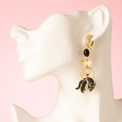 Maak een gedurfde indruk met deze asymmetrische statement oorbellen, versierd met een krachtige zwarte zirkonia panter en een sprankelende zwarte zirkonia bloem bedel. Deze unieke oorbellen combineren stoerheid met elegantie, perfect voor de krachtige vrouw die graag opvalt. De gedurfde zwarte zirkonia voegt een luxe uitstraling toe, terwijl het asymmetrische ontwerp een speelse twist geeft aan elke look.