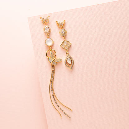 Deze prachtige asymmetrische oorbellen zijn een waar statement. De stekers zijn in de vorm van een elegante vlinder, die een verfijnde en delicate uitstraling geeft. De oorbellen zijn verder versierd met schitterende zirkonia en parelmoer stenen, wat zorgt voor een luxe en sprankelend effect. Een subtiele fringe van zirkonia steentjes voegt een speels en sierlijk element toe aan het geheel.